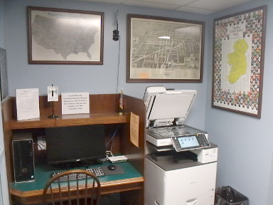 [photo: computer, photocopier, and framed maps]